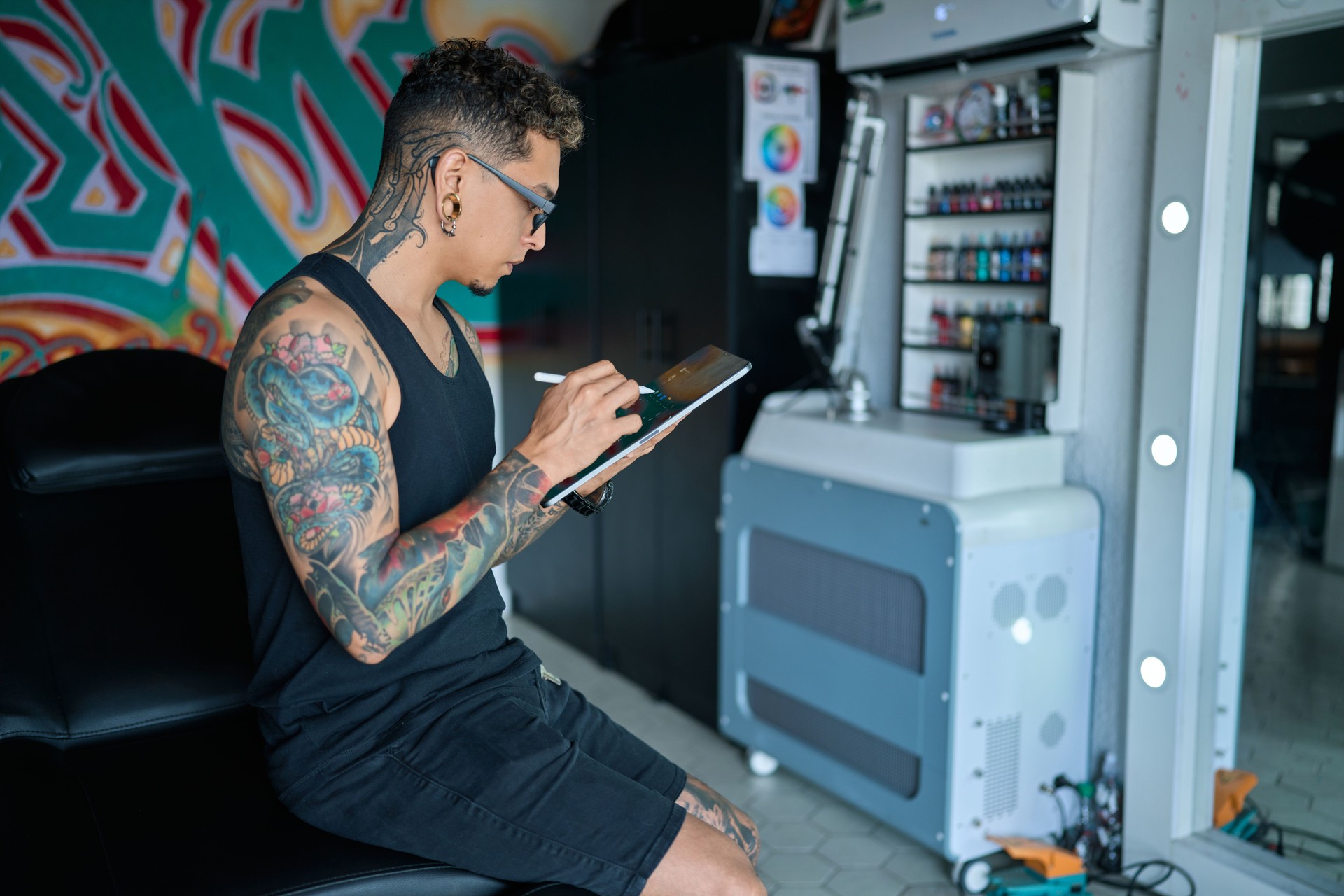 Tattoo artist drawing new tattoo design using a digital tablet in his modern studio, preparing for next client